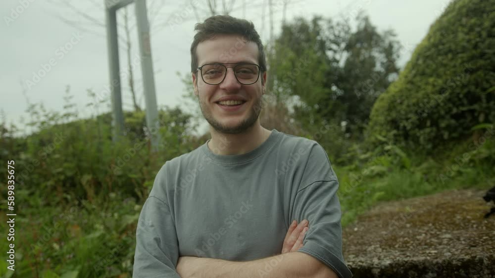 Handsome Young Man Smiling at the Camera While Crossing His Arms in Nature Handsome Young Man Smiling at the Camera While Crossing His Arms in Nature