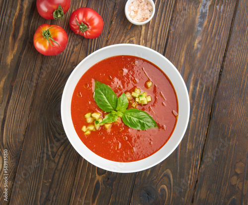 Gazpacho soup with tomatoes and basil on wooden table. Top view flat lay