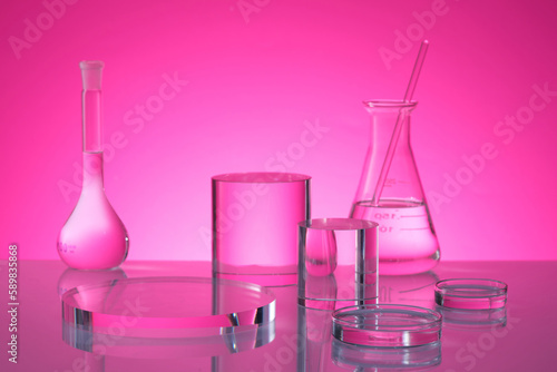 Transparent podium in round and cylinder shape are decorated on pink background with laboratory glassware containing fluid. Stage showcase on pedestal