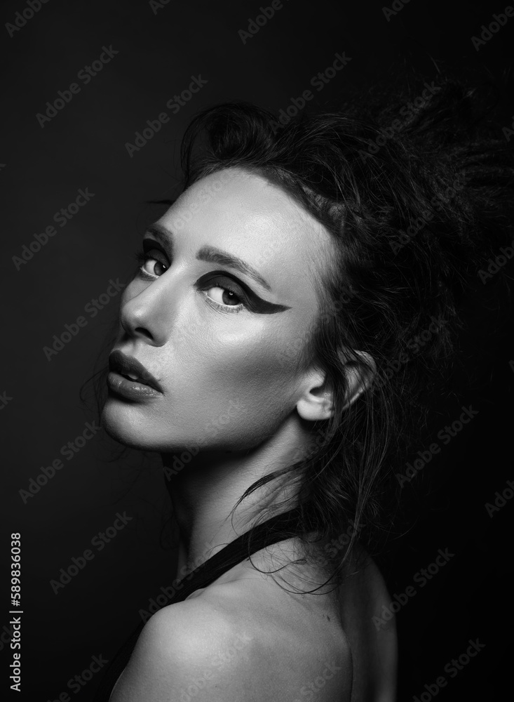 Fashion and make-up concept. Studio portrait of beautiful woman with red shadows, long and dark dreadlocks hair looking at camera with seductive look. Studio shot. Black and white image Fashion and make-up concept. Studio portrait of beautiful woman with red shadows, long and dark dreadlocks hair looking at camera with seductive look. Studio shot. Black and white image