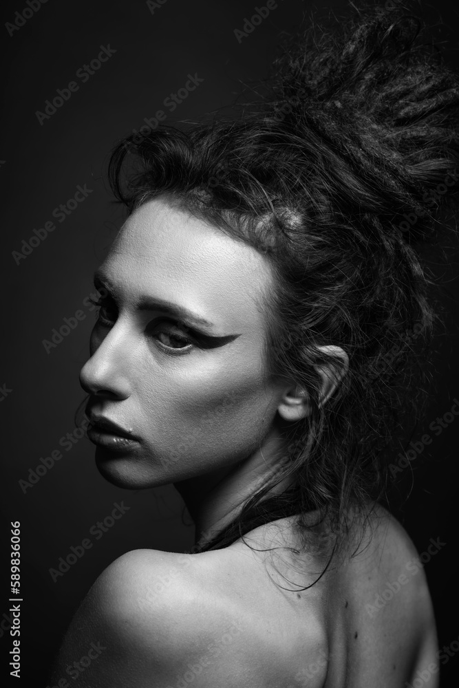 Fashion and make-up concept. Studio portrait of beautiful woman with eye shadows, long and dark dreadlocks hair looking aside camera with seductive look. Studio shot. Black and white image