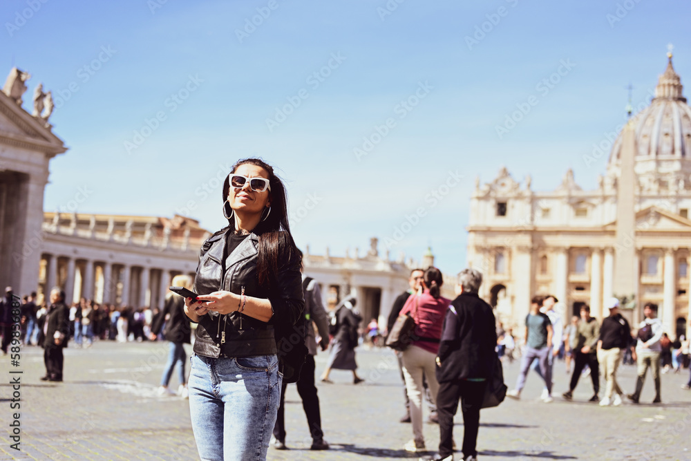 Rome,Italy, Vatican City, Rome, Saint Peter's Basilica in St. Peter's Square. Young beautiful woman using a phone  .Concept of Italian gastronomy and travel