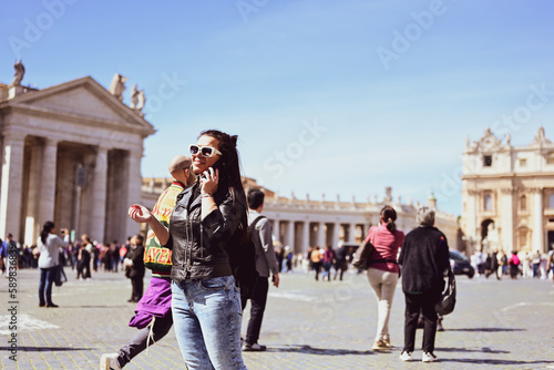 Rome,Italy, Vatican City, Rome, Saint Peter's Basilica in St. Peter's Square. Young beautiful woman using a phone .Concept of Italian gastronomy and travel