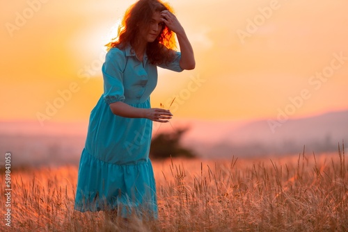 Woman with flower on field wheat with sunset background