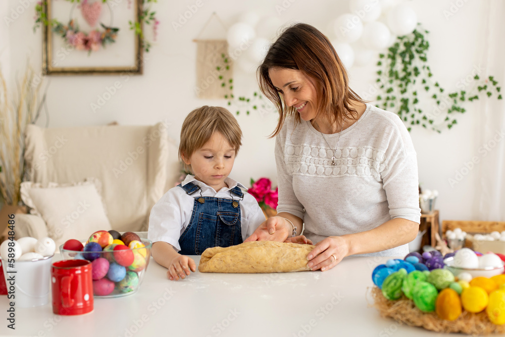 Little blond toddler child with mother, preparing dough for easter brioche buns, sweet easter bread with nuts and dry fruits Little blond toddler child with mother, preparing dough for easter brioche buns, sweet easter bread with nuts and dry fruits