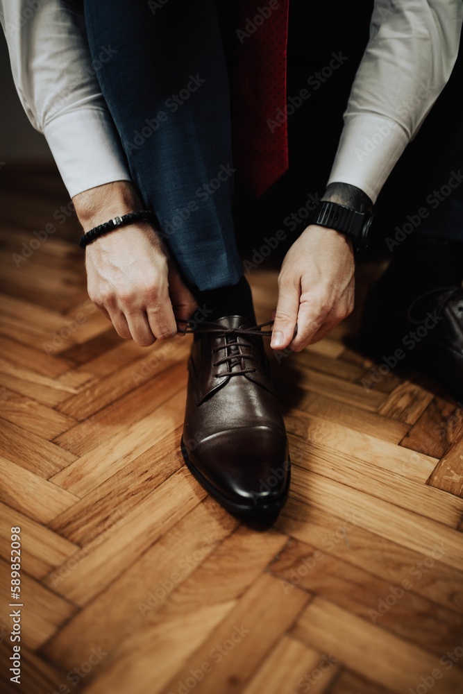 Vertical closeup of a man tying up his shoelaces of his shoes Vertical closeup of a man tying up his shoelaces of his shoes