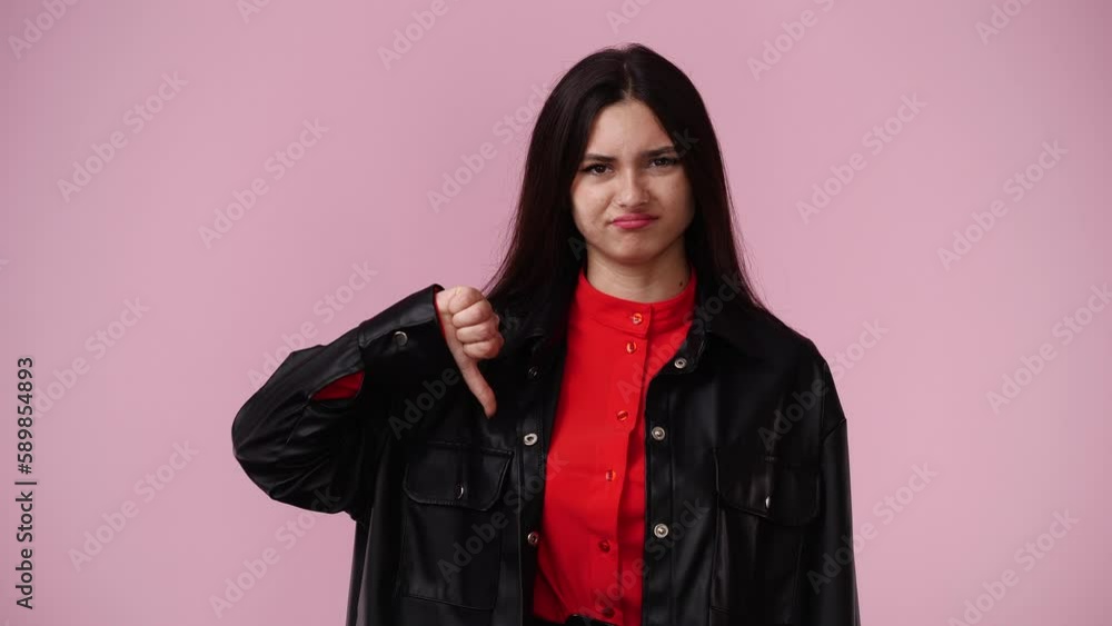 4k video of one girl with negative facial expression showing thumb down over pink background. 4k video of one girl with negative facial expression showing thumb down over pink background.