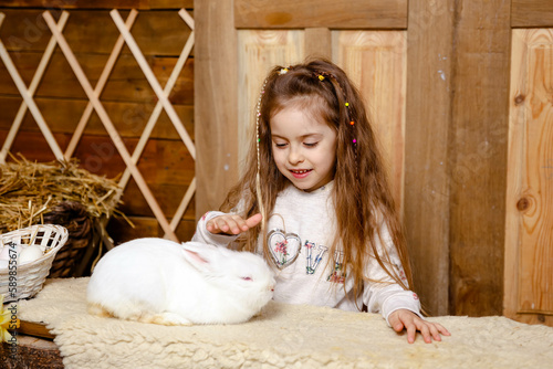 Little girl caring and feeding her loving pet food. Farming and gardening for small children. Cheerful girl looking at rabbit. Cute toddler girl with real bunny. Rabbit eating food from a persons hand