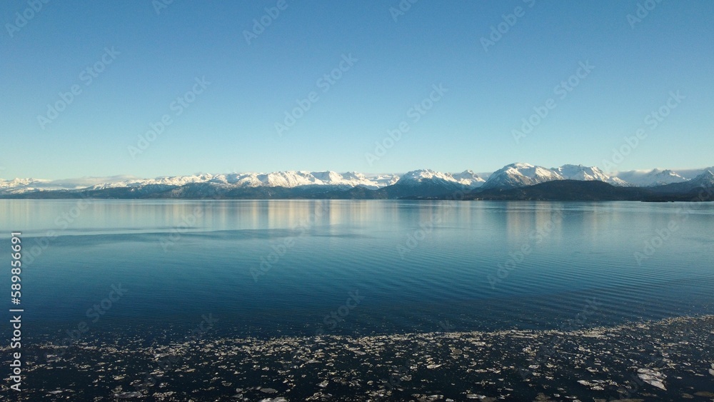 Gorgeous view of the waters in Alaska on a sunny day with snowy mountains in the background