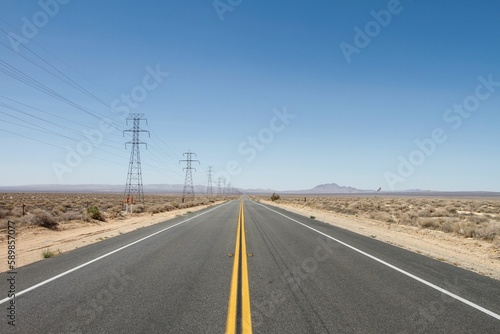 Empty highway road with dry plant fields on each side on a sunny day © Jennifer Hendershot/Wirestock Creators