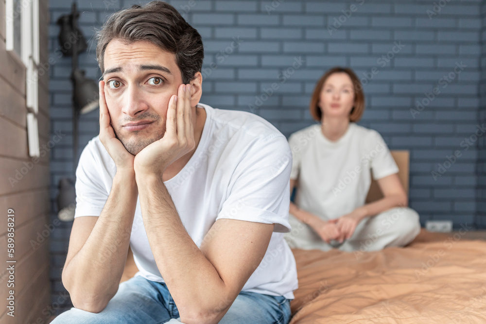 Frustrated and depressed man sitting on the edge of the bed after conflict with his wife because of his erectile dysfunction problem Frustrated and depressed man sitting on the edge of the bed after conflict with his wife because of his erectile dysfunction problem
