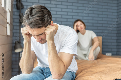 Frustrated and depressed man sitting on the edge of the bed after conflict with his wife because of his erectile dysfunction problem