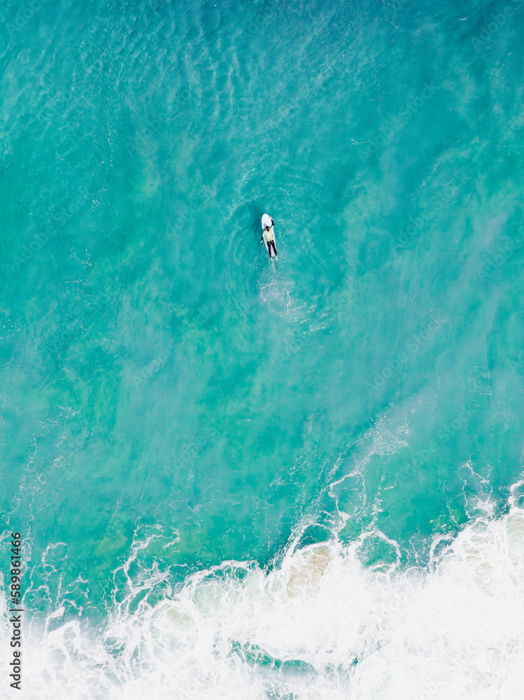 View from above, stunning aerial view of a person surfing on a turquoise ocean. Fuerteventura, Canary Islands, Spain.