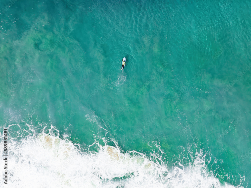 View from above, stunning aerial view of a person surfing on a turquoise ocean. Fuerteventura, Canary Islands, Spain.