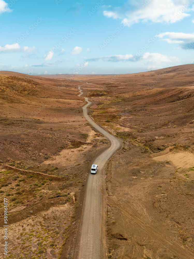 View from above, stunning aerial view of a van that travels on a deserted road in Fuerteventura, Canary Islands