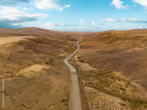Obraz na płótnie View from above, stunning aerial view of a van that travels on a deserted road in Fuerteventura, Canary Islands w salonie