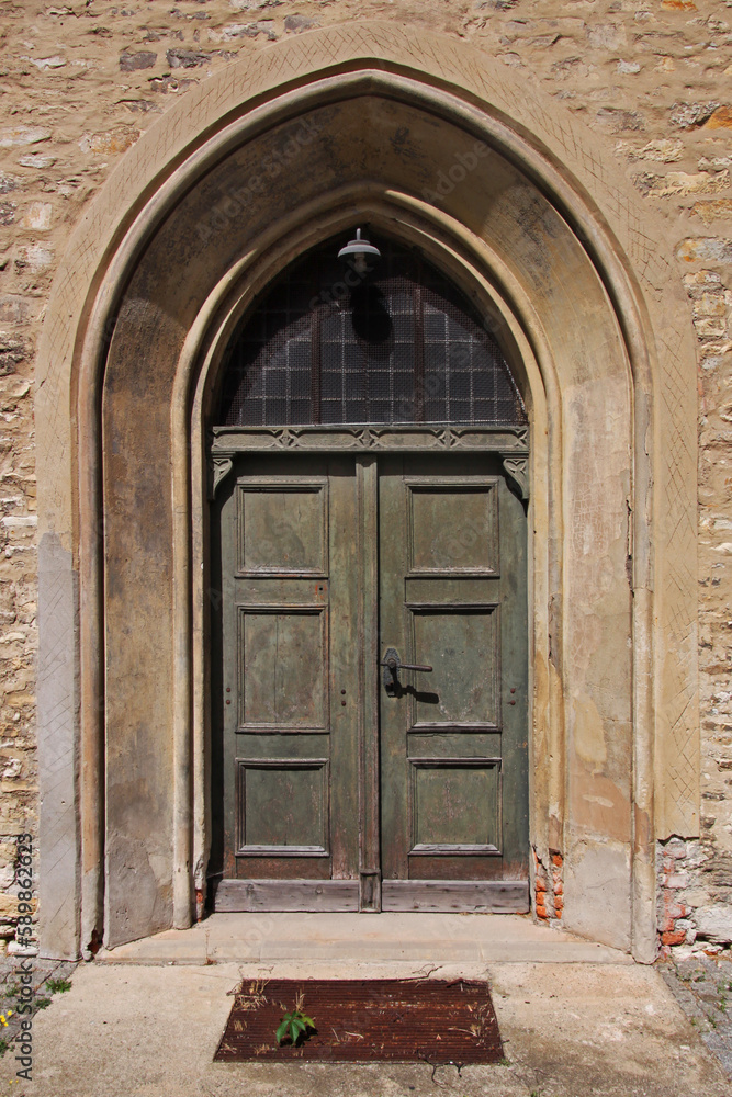 Pointed gothic arch with ancient wooden door at St. Moritz church in the old town of Halberstadt in Sachsen-Anhalt region, Germany