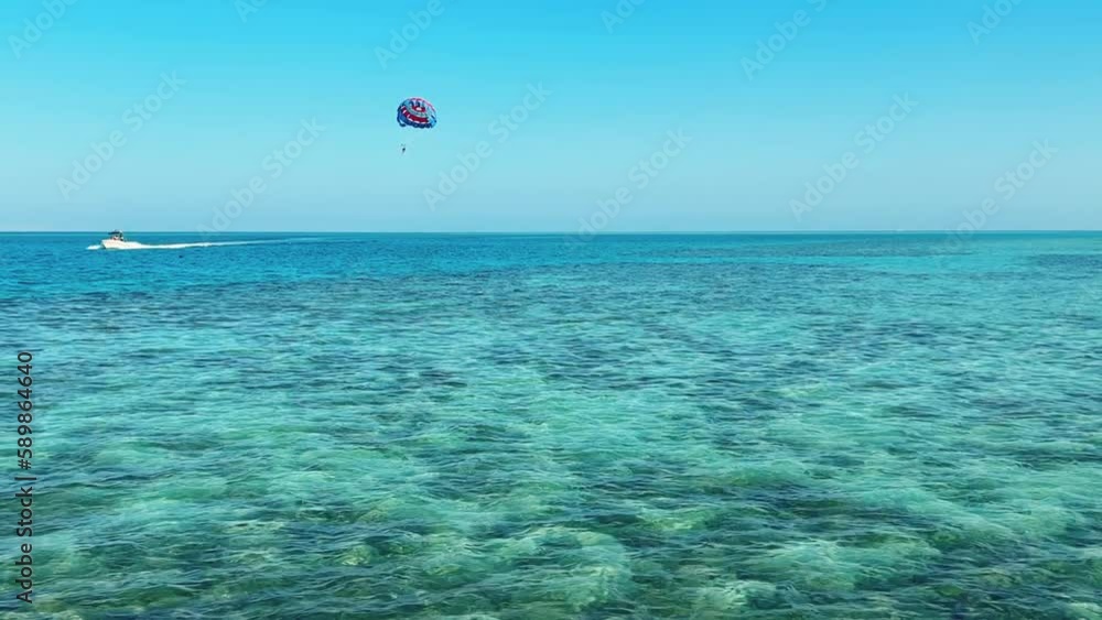 Parachute flight over the Red Sea. Blue water with sun glare and swimming fish in Egypt. The seaside resort has an all-inclusive system. Hurghada 2022 Parachute flight over the Red Sea. Blue water with sun glare and swimming fish in Egypt. The seaside resort has an all-inclusive system. Hurghada 2022