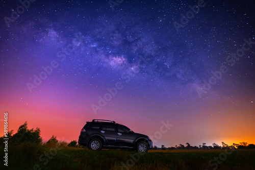 Black camp car at night with many stars before sunrise. Space background with noise and grain. Night landscape with car and colorful bright milky way.Beautiful scene with universe. 
