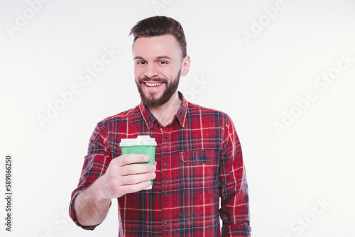 Handsome bearded man drinks coffee from paper cup. Coffee to go. Cafe concept. Coffee shop. Good morning. Happy guy enjoy fresh hot tea. Smiling barista offer you beverage.