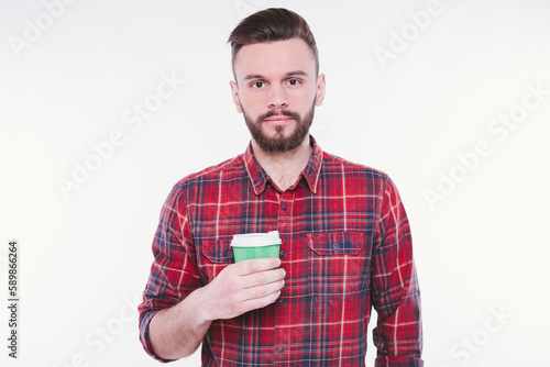 Handsome bearded man drinks coffee from paper cup. Coffee to go. Cafe concept. Coffee shop. Good morning. Happy guy enjoy fresh hot tea. Smiling barista offer you beverage.