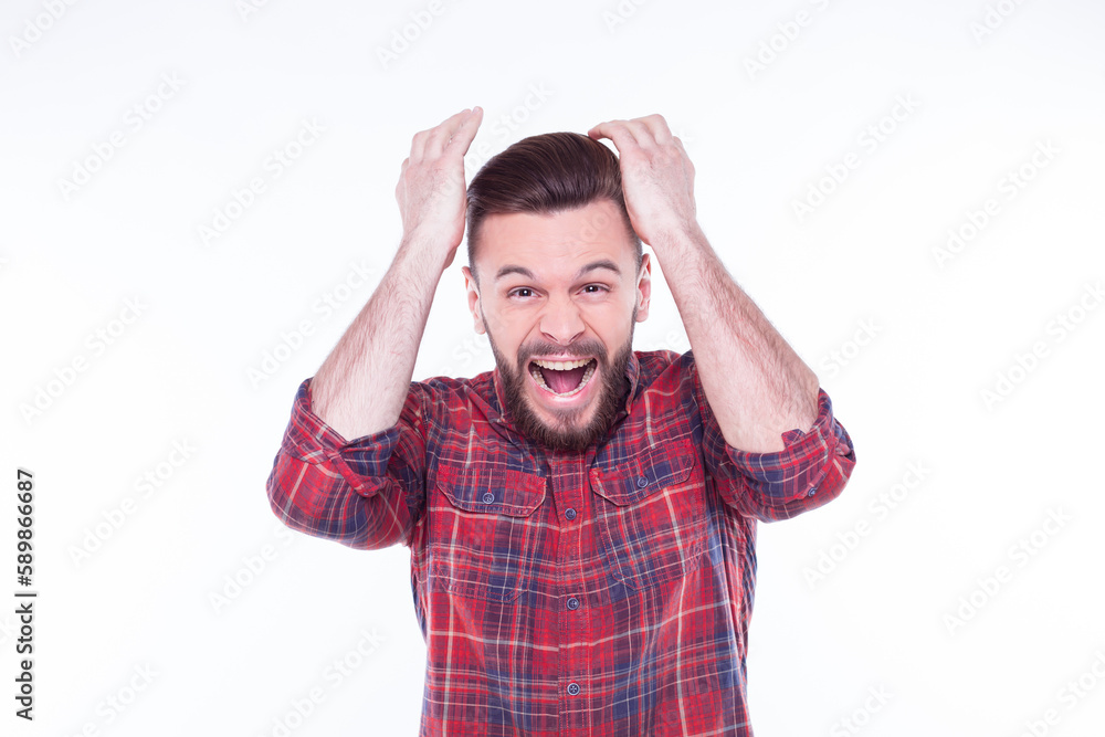 Young man wearing checkered shirt standing over isolated white background crazy and mad shouting and yelling with aggressive expression and arms raised. Frustration concept. Young man wearing checkered shirt standing over isolated white background crazy and mad shouting and yelling with aggressive expression and arms raised. Frustration concept.