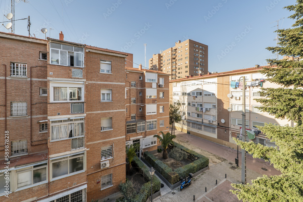 An urban landscape with facades of a cheap brick clay buildings with street trees, gardens with hedges and pedestrian streets An urban landscape with facades of a cheap brick clay buildings with street trees, gardens with hedges and pedestrian streets