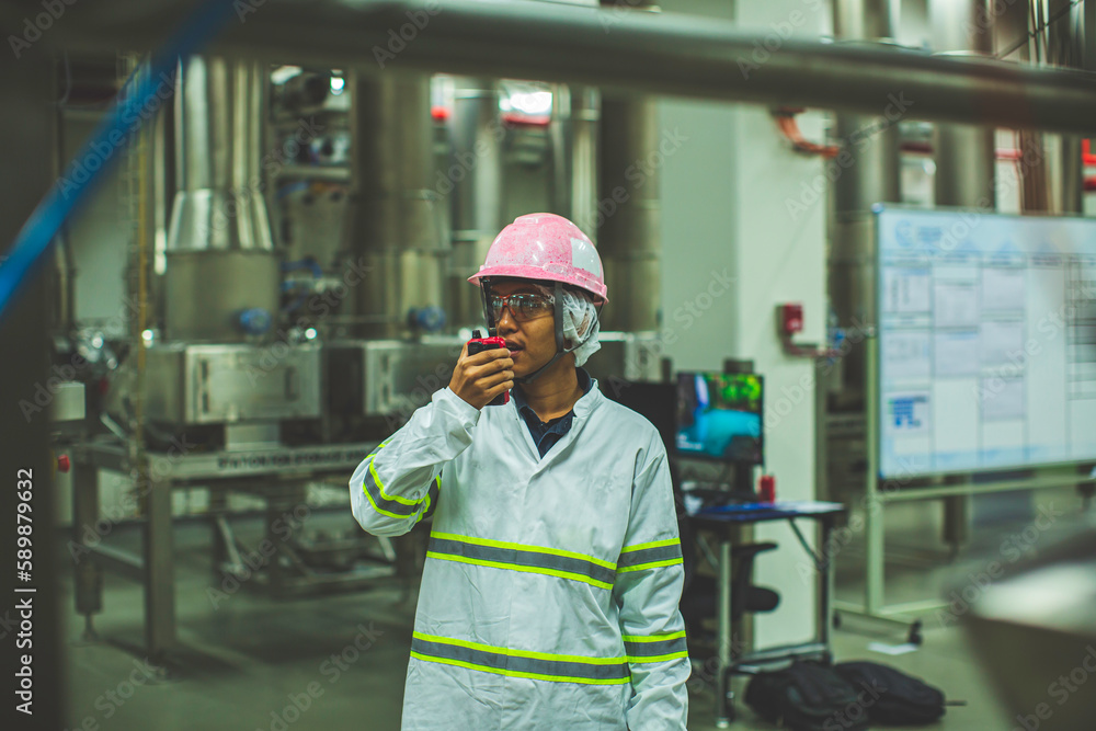 Male engineers sound protection and uniform staff.Hand holding portable radio transceiver for communication work inspection process powder stainless steel tanks Male engineers sound protection and uniform staff.Hand holding portable radio transceiver for communication work inspection process powder stainless steel tanks