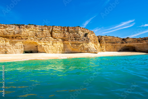 A unique front view of the empty Praia da Malhada do Baraço beach, a hidden gem with turquoise waters and yellow sand nestled in the picturesque coastline of Lagoa in the Algarve region of Portugal.
