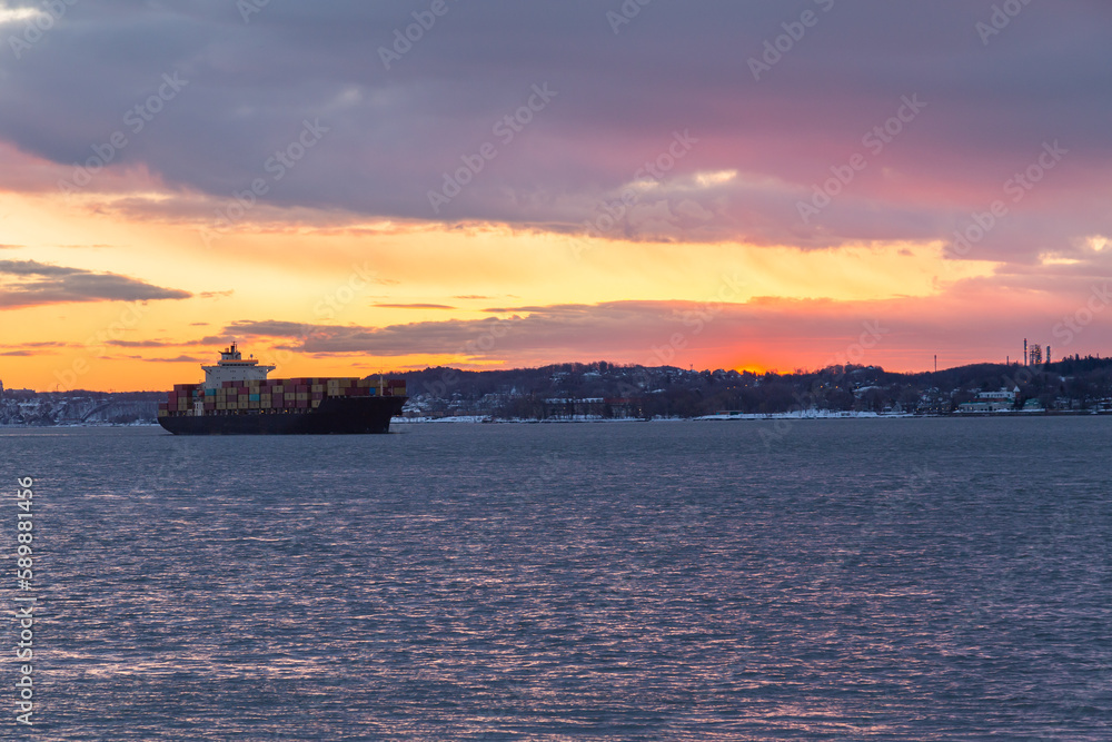 Cargo boat on the St. Lawrence River seen during a dramatic spring sunrise, with the south shore in the background, Quebec City, Quebec, Canada Cargo boat on the St. Lawrence River seen during a dramatic spring sunrise, with the south shore in the background, Quebec City, Quebec, Canada
