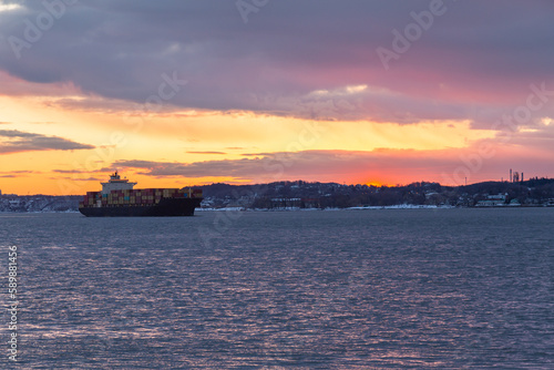 Cargo boat on the St. Lawrence River seen during a dramatic spring sunrise, with the south shore in the background, Quebec City, Quebec, Canada © Anne Richard