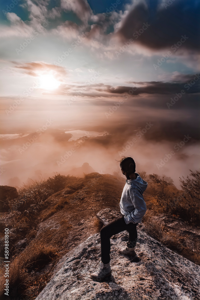 Obraz premium A Tourist enjoying with fog in Chiangmai, Thailand. A girl on the mountain with beautiful fog. The Beautiful Morning Time. Travel and tourism. Young woman on the peak of the mountain with morning fog 