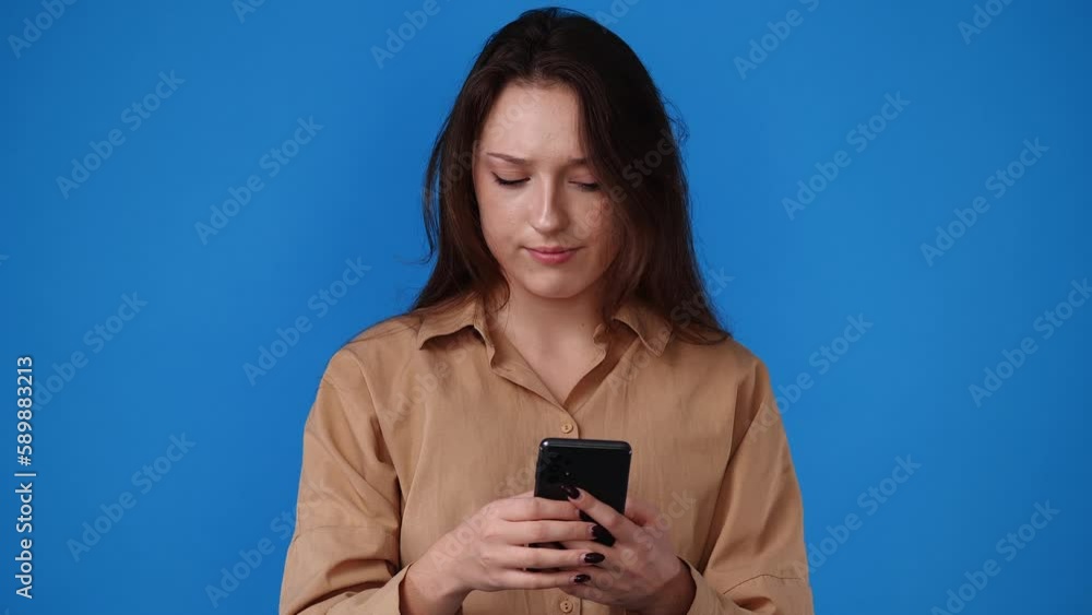 4k video of one girl typing text on the phone with a negative facial expression over yellow background. 4k video of one girl typing text on the phone with a negative facial expression over yellow background.