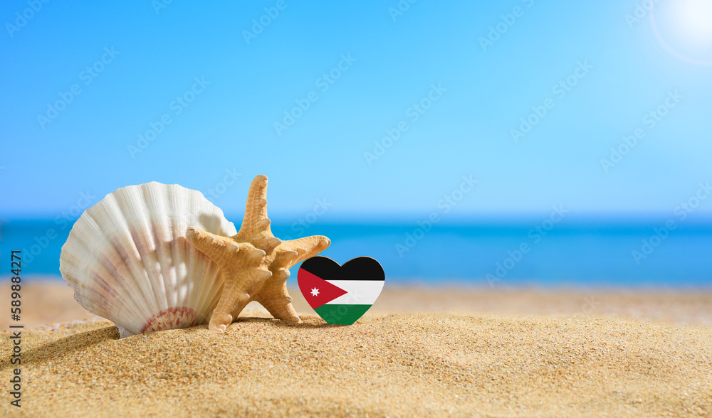 Obraz premium Beautiful beach in Jordan. Flag of Jordan in the shape of a heart and shells on a sandy beach.