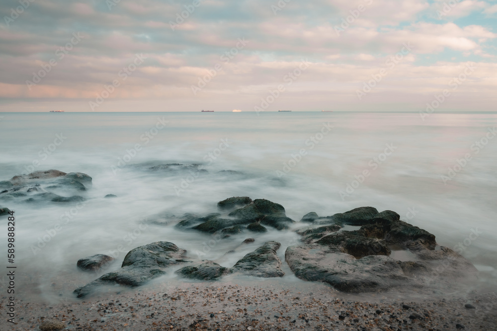 Long exposure of a sunset by the sea and a rocky coast