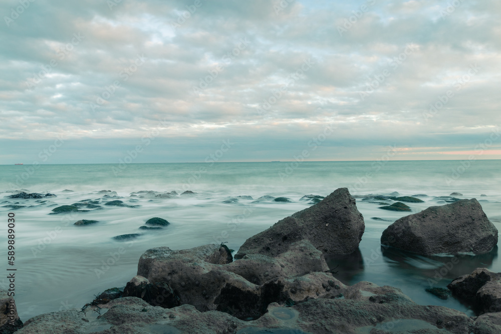 A beautiful long exposure shot of waves crashing onto the rocky shore