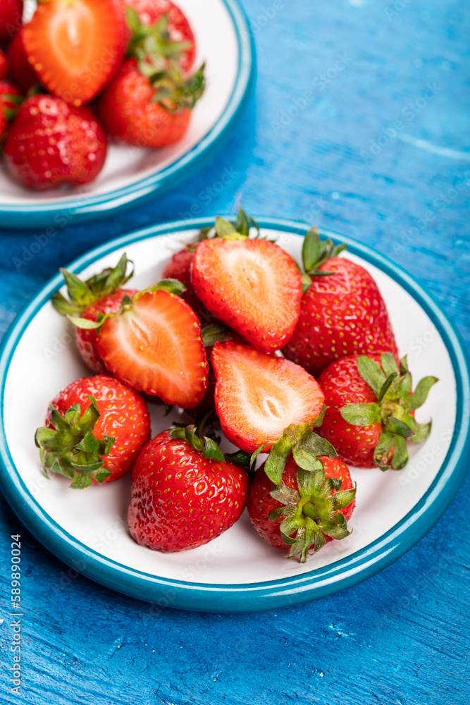 Fresh strawberries in a bowl on the blue wooden background. Close-up. Fresh strawberries in a bowl on the blue wooden background. Close-up.