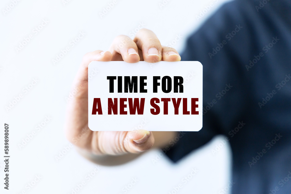 Time for a new style text on blank business card being held by a woman's hand with blurred background. Business concept about new style.
