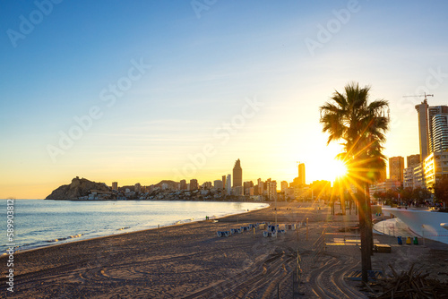 on the beach of benidorm with the skyline and fantastic sunshine through the palm trees