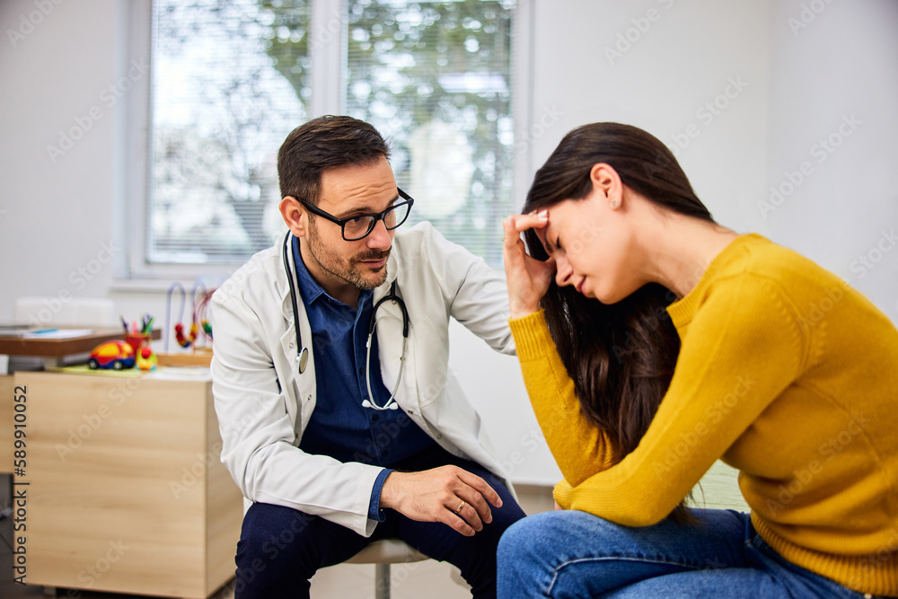 Fototapeta premium A caring male pediatrician console a worried mother after telling her child's health condition.