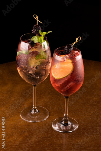 two refreshing glass of lillet spritz aperol cocktail with lemon berries and mint and ice on wooden table with top view photo