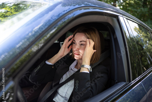 Young attractive businesswoman in suit driving and standing in a traffic jam. Tired business lady sitting in car and feeling bad because of long time of traffic light © Vitaliy