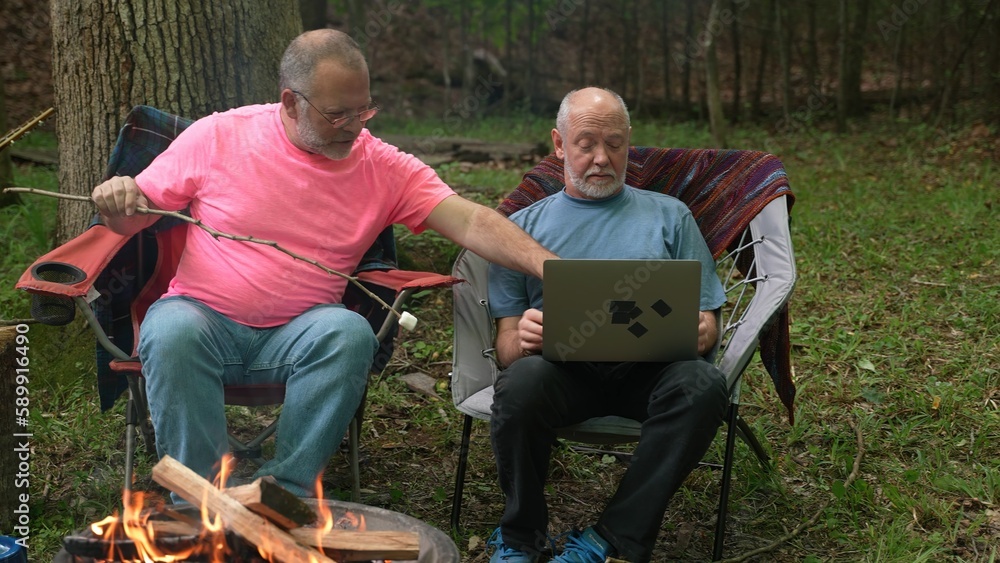 Two gay men with pride flag and tent in tent talking to laptop on video chat. Two gay men with pride flag and tent in tent talking to laptop on video chat.