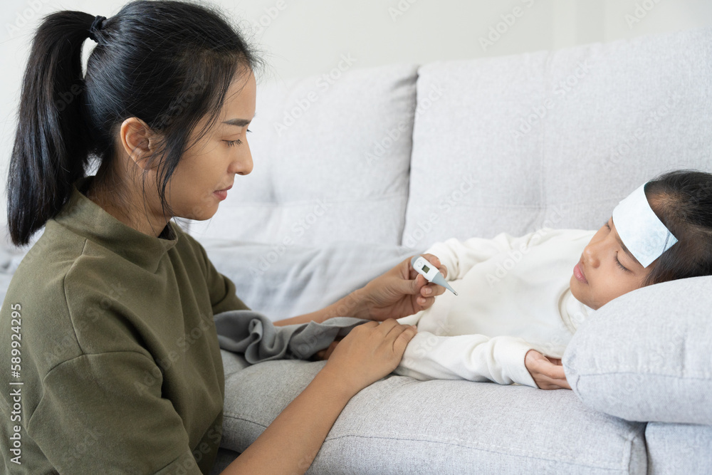 asian woman take care of little ill daughter. Sick child lying on bed
