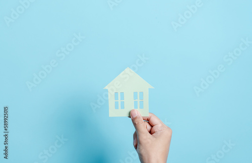 Hand holding house paper cut  family home  homeless housing  mortgage crisis and home protection insurance  international day of families  foster home care  family day care  stay home concept