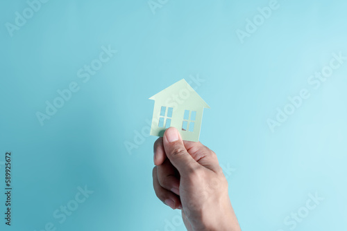 Hand holding house paper cut  family home  homeless housing  mortgage crisis and home protection insurance  international day of families  foster home care  family day care  stay home concept