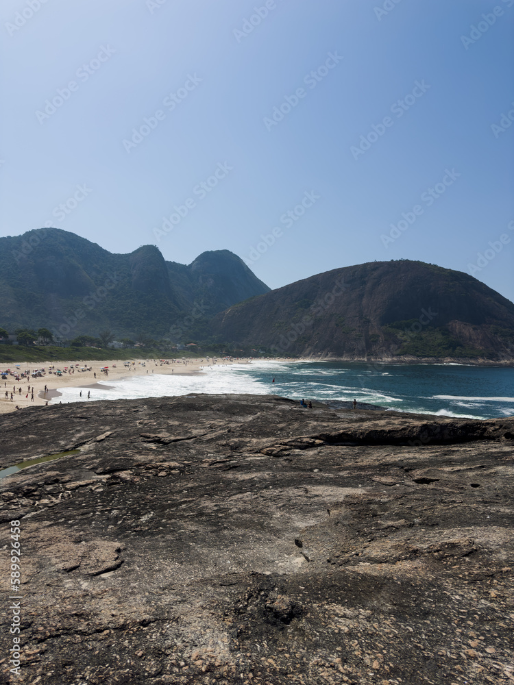 View of Itacoatiara beach in Niterói in Rio de Janeiro, Brazil with its beautiful hills surrounding the beach, big waves in a sunny summer day