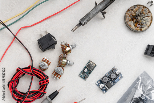 arrangement of different electrical tools on grey background. multimeter, converter, adapters, heat shrink etc.