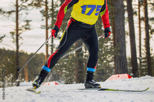 close-up male athlete skier running cross country skiing, on legs frid tag to control result