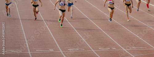 group female athletes run sprint race on stadium track, woman runner winner distance is approaching finish line © sports photos